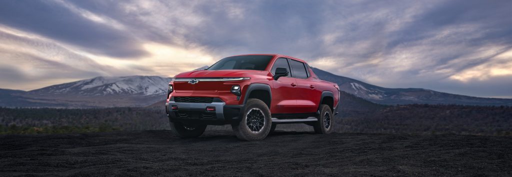 red chevy silverado ev in a mountain valley